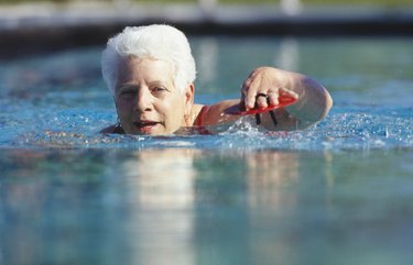 Senior woman swimming in outdoor pool, surface view