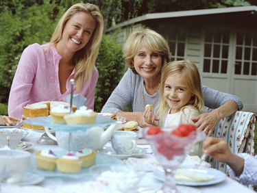 Three generation family of females at garden table, smiling