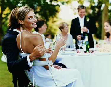 Portrait of a Bride Sitting at a Wedding Reception in a Garden With a Glass of Champagne