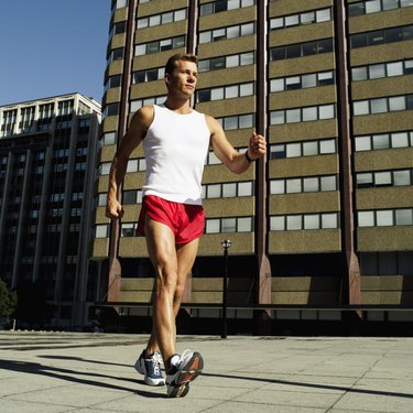 Side profile of a man wearing shorts power walking outdoors