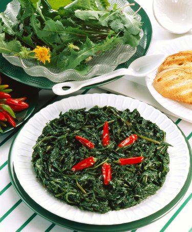 high angle view of a side dish of green garnished with chilies and served with salad and bread