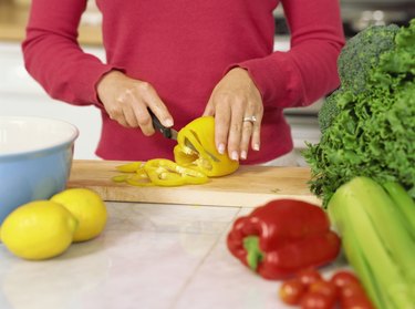 mid section view of a woman cutting a yellow bell pepper