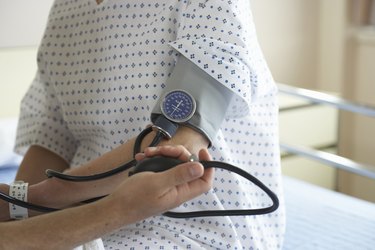 "Male doctor checking woman's blood pressure, mid section"