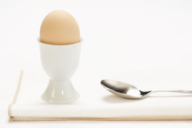 Egg in cup with spoon on cloth napkin