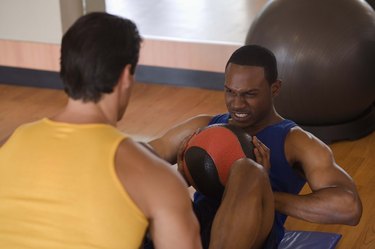 Personal trainer holding feet of man doing sit-ups