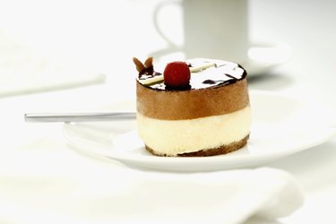 Ornate cheesecake on plate with coffee cup in background, close-up, selective focus