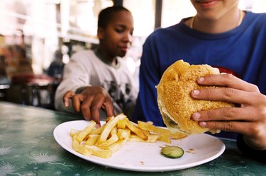 close-up of a teenagers hand stealing a French fry from someone else's plate