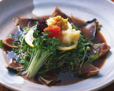 Slices of bonito with soy sauce on plate, high angle view, differential focus