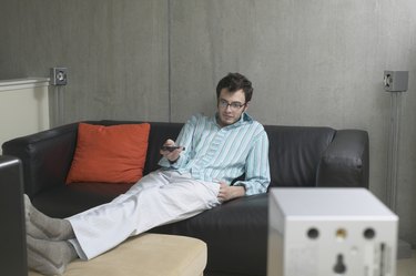 View of a man lounging on a couch and watching television