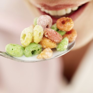 Close-up of a person's mouth eating a spoon full of breakfast cereal with milk