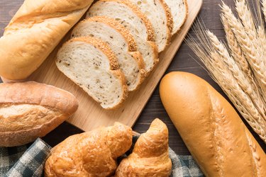 Fresh baked bread and wheat on wooden background