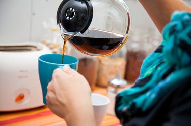 woman pouring coffee pot  into coffe mug