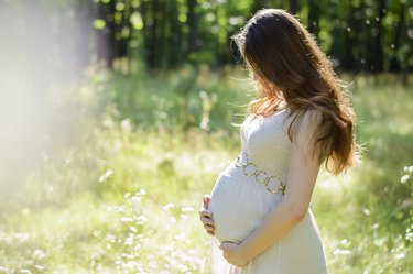 pregnant person holding belly in field