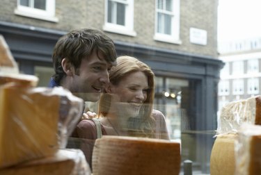 Young couple looking in store window, view from inside store