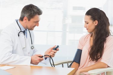 Male doctor checking blood pressure of a woman