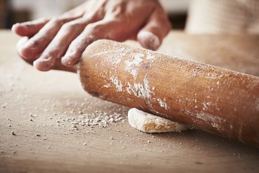 Hands baking dough with rolling pin