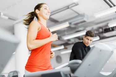 Beautiful young woman running on a treadmill in gym