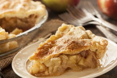 A slice of apple pie with calories on a white plate