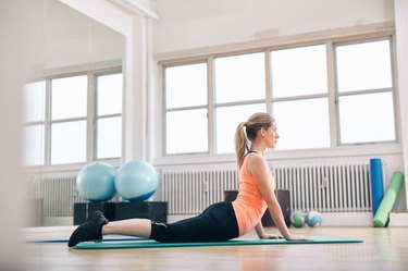 Woman doing core stretch on fitness mat. Attractive young woman doing yoga at gym.