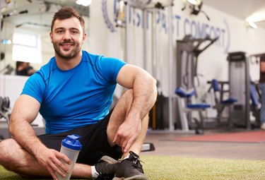 Young man drinking water in a gym