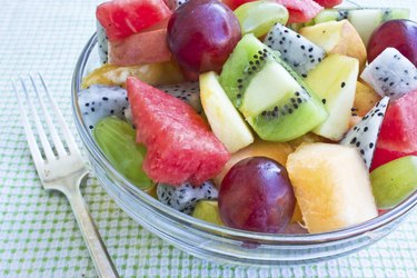 small glass bowl filled with bites of kiwi, watermelon, pineapple, dragon fruit, grapes and more.
