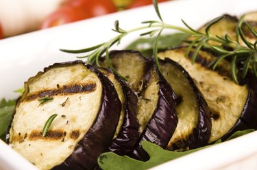 Grilled eggplant slices on a plate with fresh rosemary