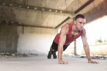 Muscular, athletic built, young man doing pushups in an abandoned ruin building