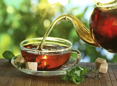 Pouring tea from a teapot into a cup.