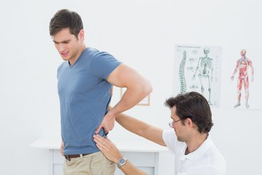 Side view of a male physiotherapist examining mans back