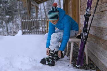 Woman adjusting ski boots in snow