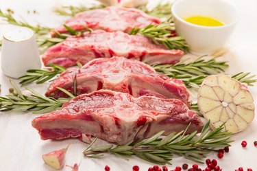 Raw fresh lamb with rosemary and garlic on wooden background