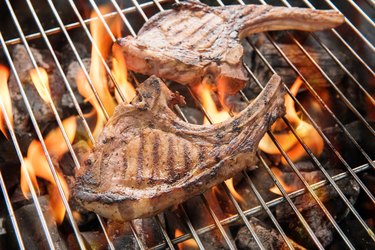 Grilled pork steaks over flames on the grill.