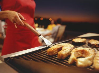 Woman barbecuing, close-up, mid section