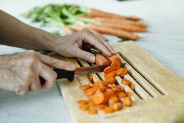 Germany, Berlin, Senior man cutting carrots