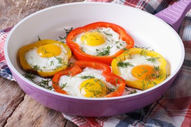 fried eggs with yellow and red peppers in pan horizontal