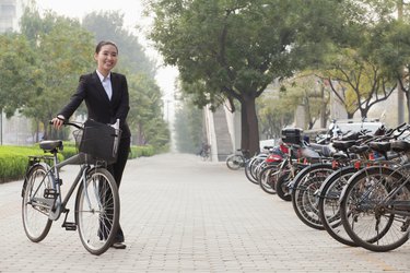 年轻的女商人抱着自行车，人行道，北京