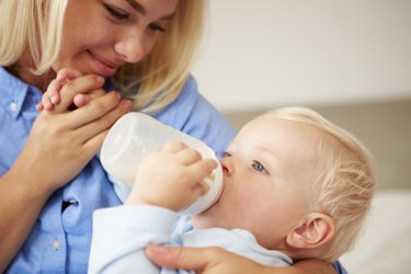 Mother Giving Baby Son Bottle Of Milk