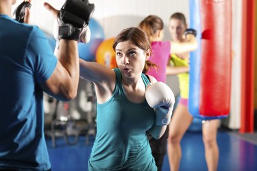 Female kick boxer with trainer in sparring