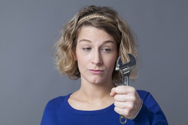 questioning 20s woman holding wrench for mechanics DIY