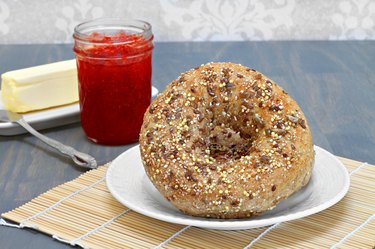 Whole grain bagels with jam and butter on the side.