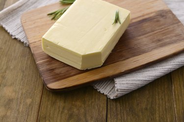 Tasty butter on wooden cutting board