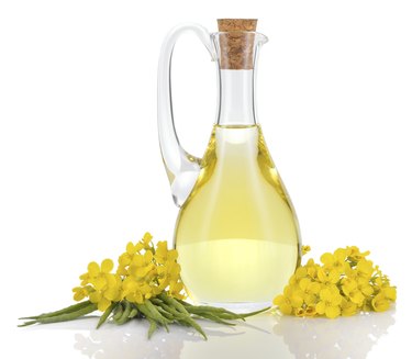 Rapeseed oil and flowers isolated over white.