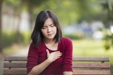 Woman Has Chest Pain Sitting on Bench at Park