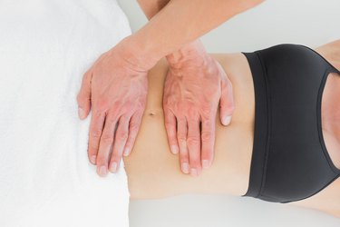 Mid section of a physiotherapist massaging woman's body