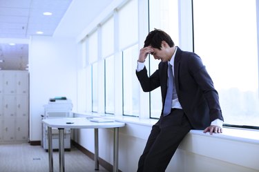 young businessman in a suit holding his head due to blood sugar drop