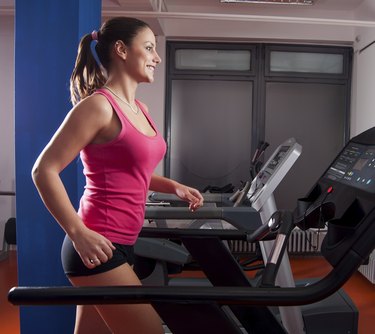 Beautiful smiling girl running on treadmill