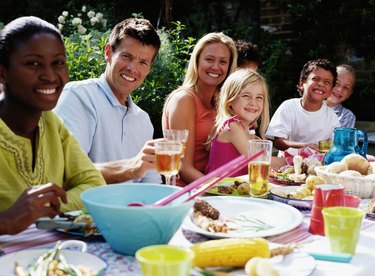 Group of people at lunch table outdoors, smiling, portrait