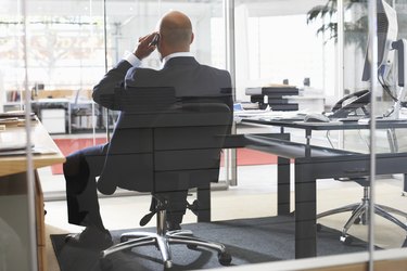 Businessman using telephone in office, rear view