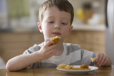 Caucasian boy eating chicken nuggets
