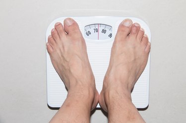 top-down photo of two feet standing on a bathroom weight scale